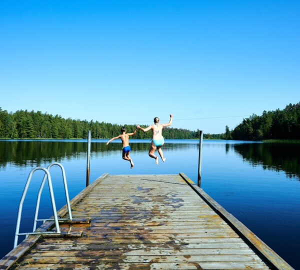 Frau und Kind springen vom Steg in den See