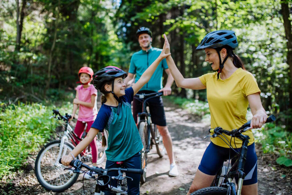 Familie klatscht im Wald bei der Radtour ab.