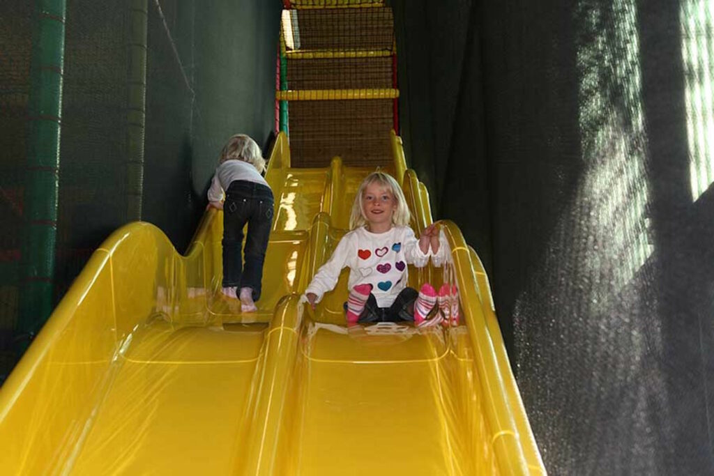 Zwei Kinder rutschen im Regenbogenland.
