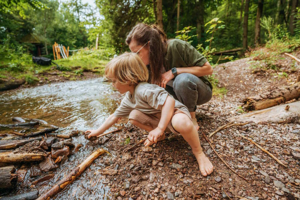 Mutter und Kind am Bach im Wald
