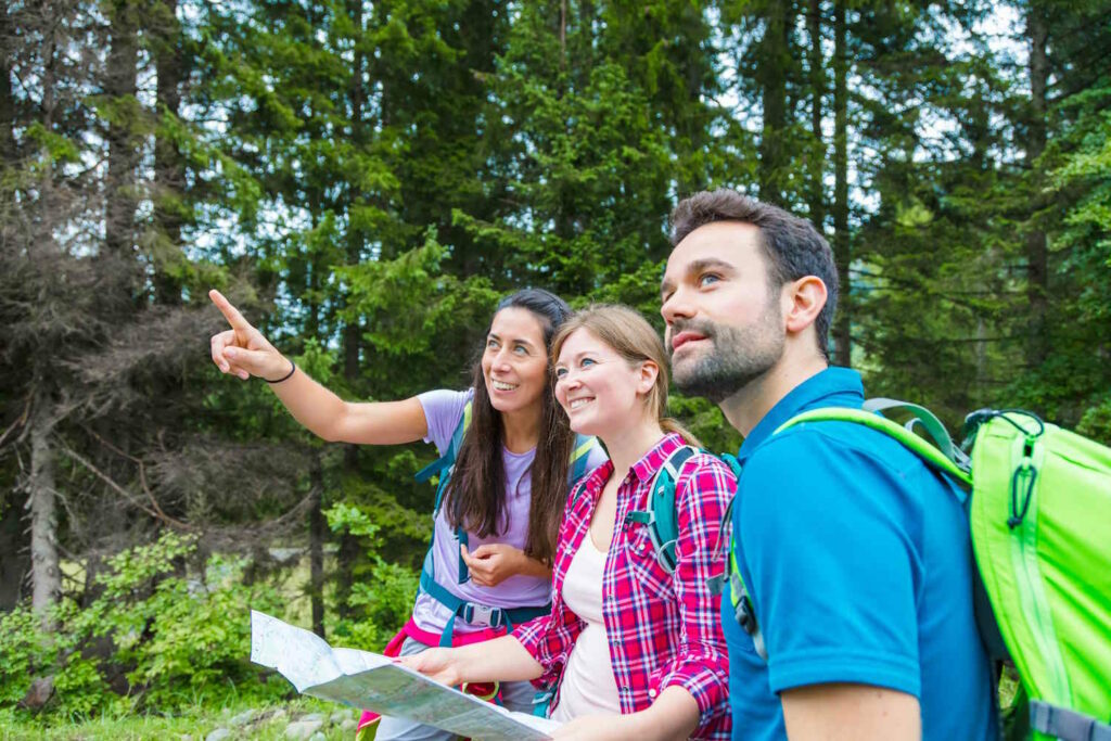 Drei Wanderer lesen Karte im Wald