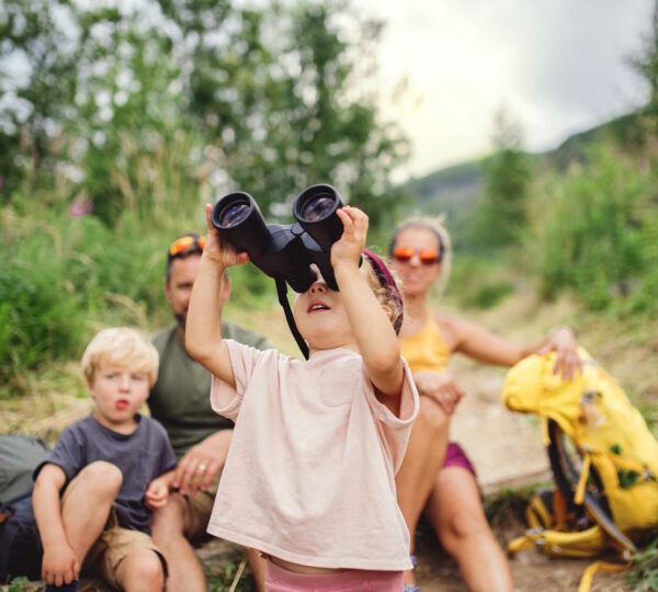 Familie beim Wandern mit Kinder, dass durch ein Fernglas schaut.