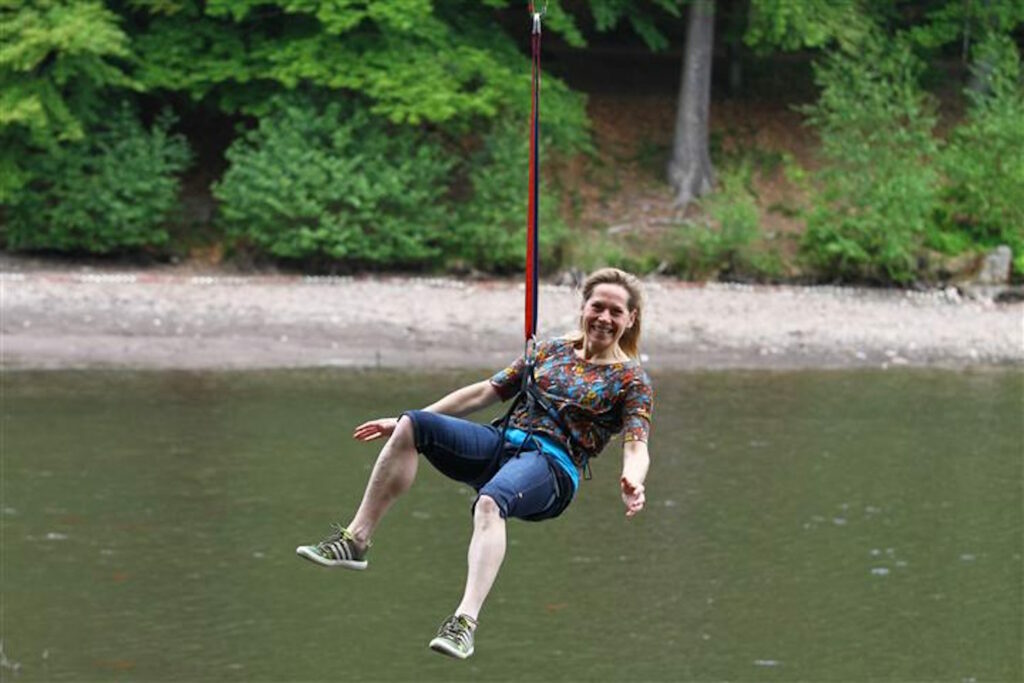 lachende Frau fliegt mit dem Flying Fox über den Schmelzteich in Bad Sachsa